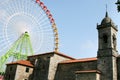 New colourful Ferris wheel and old spanish church