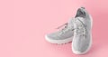 New comfortable sneakers, gray sports shoes with laces on a colored pink background with copy space