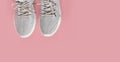 New comfortable sneakers, gray sports shoes with laces on a colored pink background with copy space