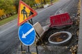 Concrete ring, metal cover of well of underground city communications on the road and metal tripod with worn signs Royalty Free Stock Photo