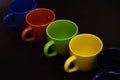 New cups, mugs of different colors are in every kitchen arranged in a straight line on a black background