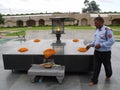 A watchman places flowers at the Mahatma Gandhi Raj Ghat Memorial and fans the eternal flame