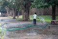 Caretaker worker waters the grassy lawn and plants at Humayan`s Tomb