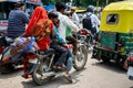 Dangerous travelling in India. The whole family, husband, wife and children on one motorcycle in traffic jam