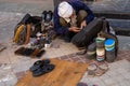 Indian craftsman cobbler fixes a broken zipper on a backpack in a market