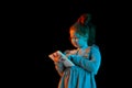 New device. Portrait of cute redheaded little girl wearing festive dress using tablet isolated over dark background in