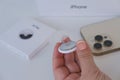 new electronic tracker Apple Airtag in female hand, iPhone 14, tracker broadcasts secure signal Bluetooth, received nearby devices