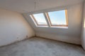 New empty mansard room with skylight windows under construction. Plaster walls. New home. Concrete walls. Interior renovation Royalty Free Stock Photo