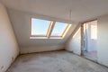 Empty mansard room with skylight windows under construction. Plaster walls. New home. Concrete walls. Interior renovation Royalty Free Stock Photo