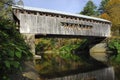 New England covered bridge spanning over a calm river with autumn reflection