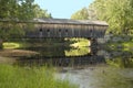 New England covered bridge spanning over a calm river with reflection