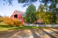 New England red barn with vivid shadows of oak trees and white picket fence Royalty Free Stock Photo