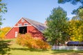 New England red barn with white picket fence and fall colors. Blue, sunny sky Royalty Free Stock Photo