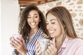 New family habits: multiracial female couple they drink a cup of tea on the porch of their country house - Two beautiful young Royalty Free Stock Photo