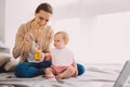 Careful babysitter holding a jar of baby food while feeding a toddler