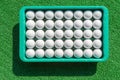 New golf balls in tray on green grass for golf practice. Royalty Free Stock Photo
