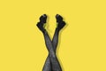 New gray female boots with bright yellow laces on long slender crossed woman legs in gray tights isolated on yellow background.