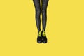New gray female boots with bright yellow laces on straight, long slender woman legs in gray tiger print tights isolated on yellow