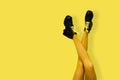 New gray female boots on long slender crossed woman legs in bright yellow tights isolated on yellow background. Pop art concept