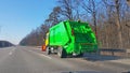 A new green garbage collection vehicle is moving along the highway. Transportation of human waste products. Disposal of municipal