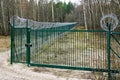 A new green metal mesh fence with coiled barbed wire and gate around the restricted area