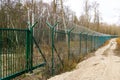 A new green metal mesh fence with coiled barbed wire and gate around the restricted area