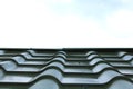 Roof of house made of iron shingles against blue sky background closeup Royalty Free Stock Photo