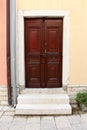 New hardwood family house entrance doors with decorative details and baroque style door handle mounted on stone frame wall next to