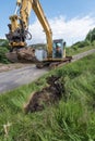 A New Holland excavator digging a ditch..