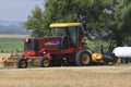 New Holland Swather in a farm field with blue sky and green tree`s on a summer day. Royalty Free Stock Photo