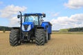 New Holland Tractor and Agricultural Trailer on Field in Autumn Royalty Free Stock Photo