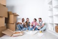 New home. Friends sitting on the floor in the new apartment and eating pizza after unpacking. Royalty Free Stock Photo