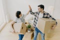 New home. Happy woman and man celebrate moving to new apartment, pose in empty room with cardboard boxes and couch in background, Royalty Free Stock Photo