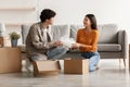 New home. Happy young Asian couple unpacking their belongings from cardboard boxes on moving day Royalty Free Stock Photo