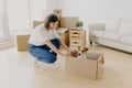 New home, moving day and relocation concept. Positive brunette woman plays with pedigree dog in carton container, unpack boxes Royalty Free Stock Photo