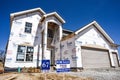 New home partially finished, under construction in residential housing subdivision with for sale sign in yard Royalty Free Stock Photo