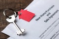 New home purchase and sale agreement. Key with keyring and blank on a brown wooden table. concept of buying a home Royalty Free Stock Photo