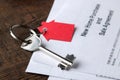 New home purchase and sale agreement. Key with keyring and blank on a brown wooden table. concept of buying a home Royalty Free Stock Photo