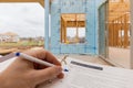 A new home under construction and man hand with pen reviewing new home financing checklist Royalty Free Stock Photo