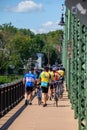 Group of bicyclists are seen on the sidewalk crossing the New Hope - Lambertville Bridge on a sunny day. They are wearing helmets