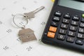 New house purchase, mortgage schedule reminder or real estate payment day, silver house keyring with calculator on white clean