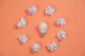 New idea concept with crumpled office paper and white light bulb on orange background. creative solution during brainstorming Royalty Free Stock Photo