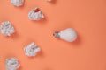 New idea concept with crumpled office paper and white light bulb on orange background. Creative solution during brainstorming. Royalty Free Stock Photo