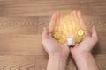 New idea concept, young women hand holding light bulb and coins on wooden backgrounds and new idea concept save power to save the Royalty Free Stock Photo
