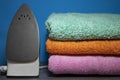 New Iron and Ironing Towels on the Table. Iron Irons linen. Pile of Clean Stacked Home Textile Items Near Blue Wall. Cozy House, Royalty Free Stock Photo