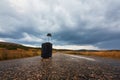 New journey, adventure and travel concept. Suitcase with cap on empty road. Nature landscape and stormy sky. Copy space Royalty Free Stock Photo