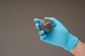 New kitchen metal wire scrubber held in hand by Caucasian male hand wearing a blue latex glove. Close up studio shot, isolated on Royalty Free Stock Photo