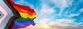 New LGBTQ rainbow flag with black and grey asexual stripes waving in the wind at cloudy sky. Freedom and love concept. Pride month