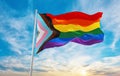 New LGBTQ rainbow flag with black and grey asexual stripes waving in the wind at cloudy sky. Freedom and love concept. Pride month