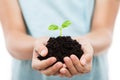 Human hand holding green sprout leaf growth at dirt soil